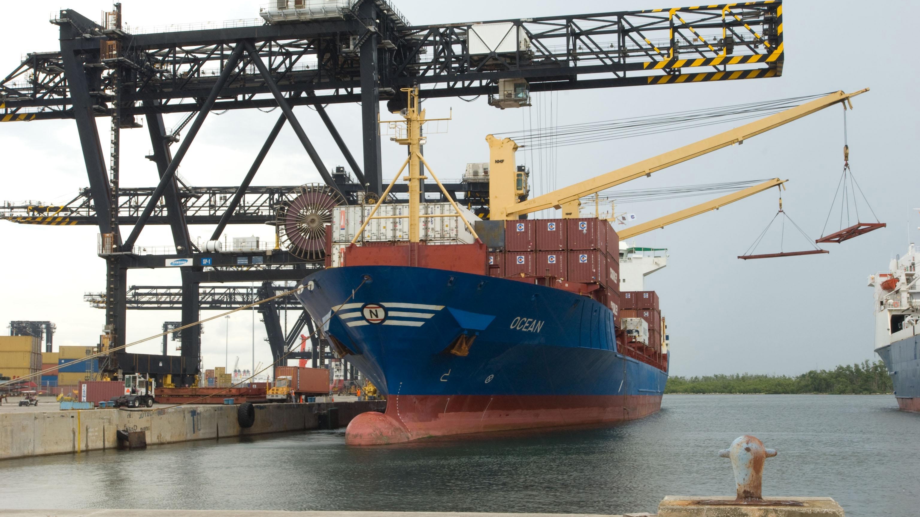 Blue cargo ship docked with cargo containers on deck