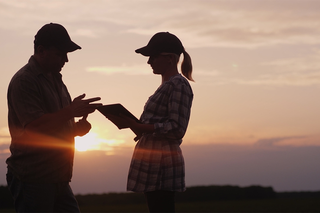 Mentor and student intern stand together at sunset to discuss the day