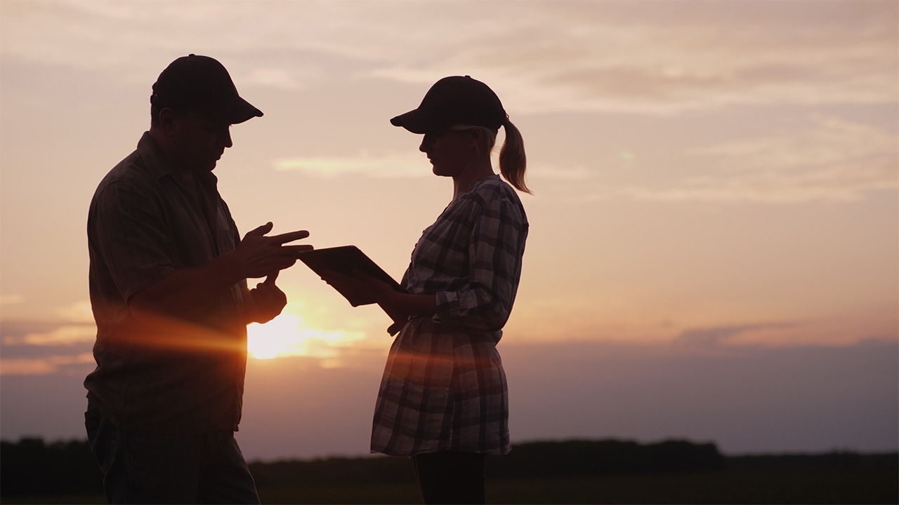 Mentor and student intern stand together at sunset to discuss the day