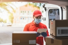 Express Courier Driver holding clipboard by boxes in the back of the van.